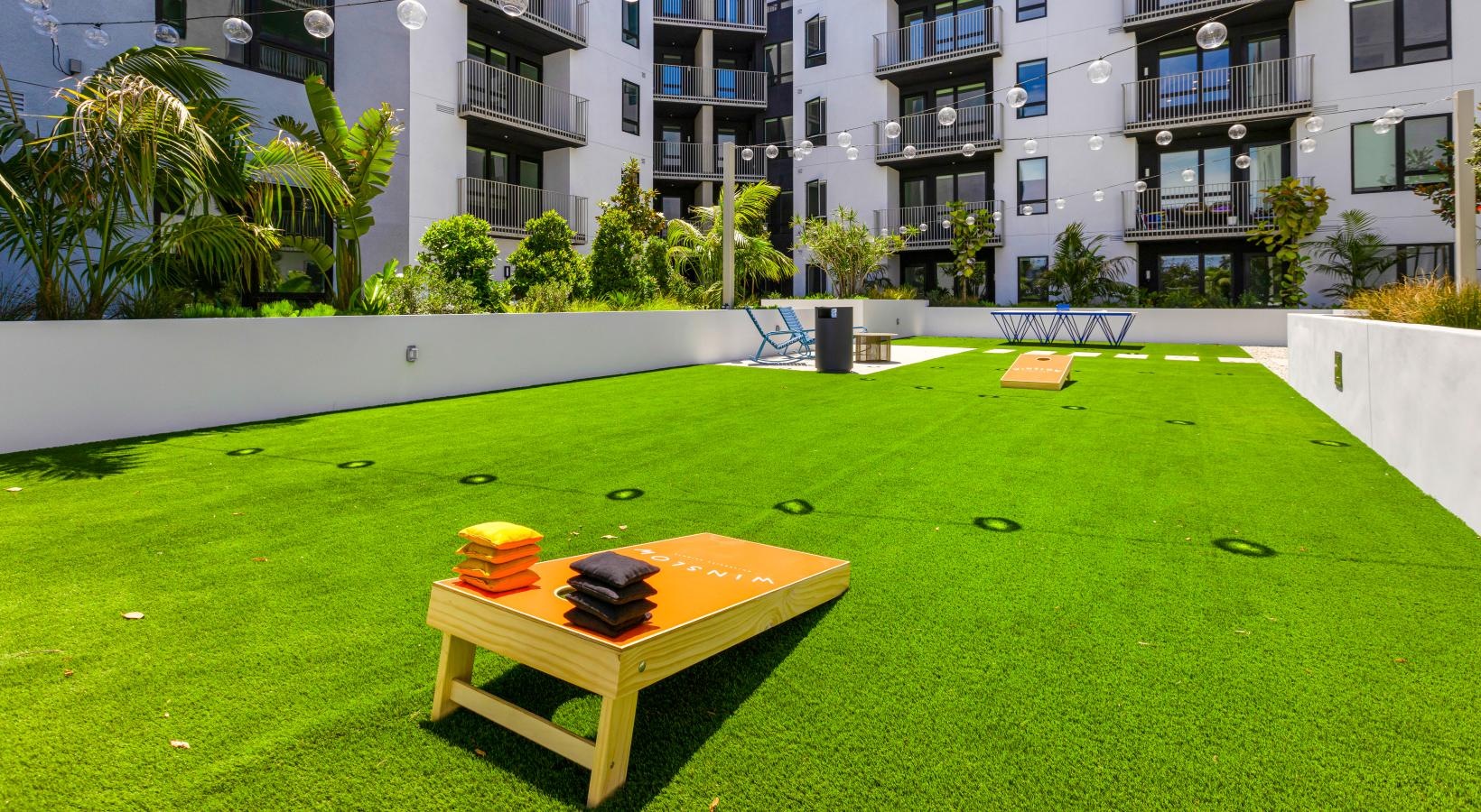 Everything within reach a large green lawn with a table and chairs and a building with balconies